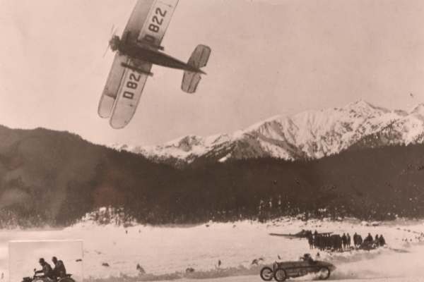 Historisches Foto eines Doppeldeckers mit den Bergen im Hintergrund